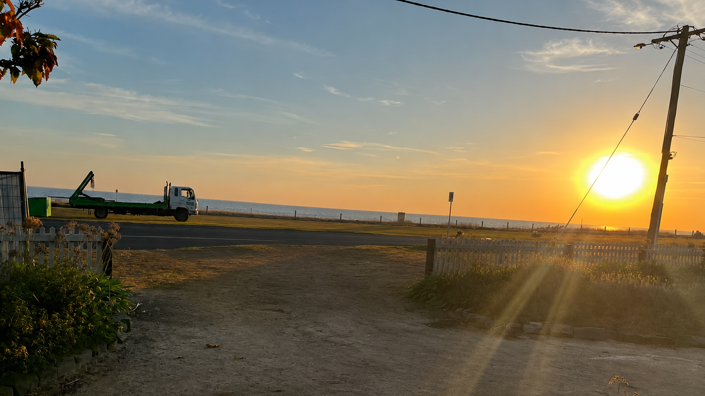 Sunset over a rural landscape with a truck on a dirt road.